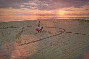 Junge und Mädchen Bruder und Schwester Zeichnung Herz-Form in Sand auf ruhigen Sonnenuntergang Strand - HOXF01406