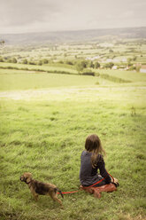 Girl with puppy dog in rural, green countryside field - HOXF01422