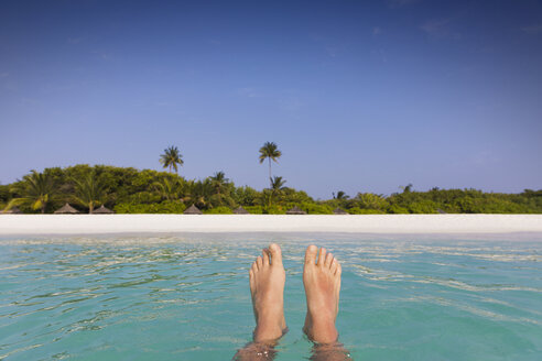 Persönliche Perspektive barfuß Mann schwimmt in tropischen Ozean mit Blick auf den Strand - HOXF01435