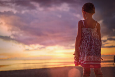 Pensive girl watching tranquil sunset in dramatic sky over ocean - HOXF01436
