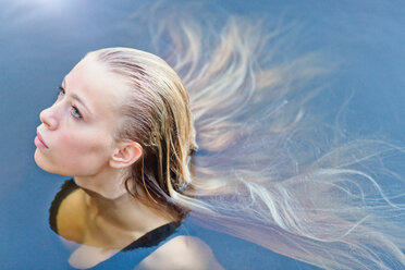 Portrait beautiful blonde teenage girl with long hair floating in swimming pool - HOXF01437