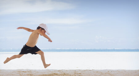 Verspielter Junge läuft am tropischen Strand - HOXF01438