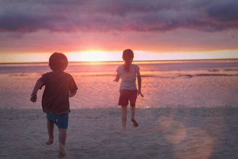 Junge und Mädchen Bruder und Schwester auf ruhigen Sonnenuntergang Strand mit dramatischen Himmel - HOXF01450
