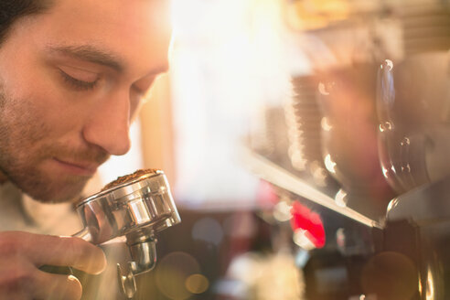 Nahaufnahme eines Barista, der an der Espressomaschine am Espressomehl riecht - HOXF01461