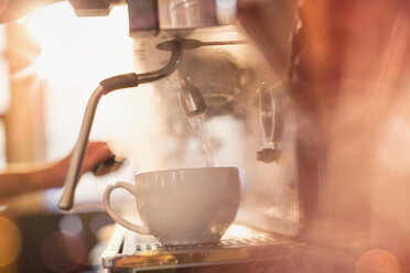 Nahaufnahme einer Espressomaschine, die eine Kaffeetasse mit heißem Wasser füllt - HOXF01463