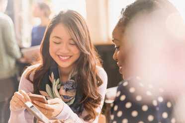 Freundinnen, die mit ihren Handys im Café SMS schreiben - HOXF01464