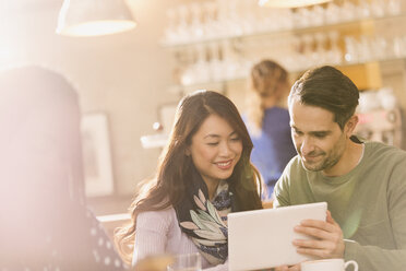 Friends using digital tablet in cafe - HOXF01465