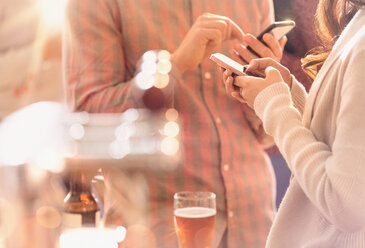 Mann und Frau telefonieren mit Handy und trinken Bier in einer Bar - HOXF01470