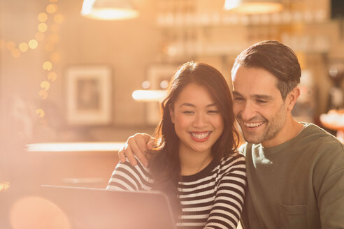 Lächelndes Paar beim Videochat am Laptop im Café - HOXF01472