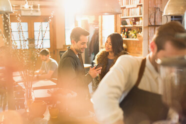 Paar benutzt Mobiltelefon in einem Café - HOXF01479