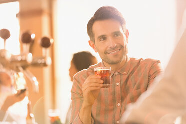 Lächelnder Mann, der an einer Bar einen Cocktail trinkt - HOXF01485