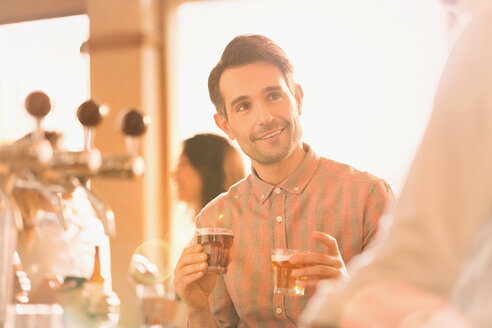 Lächelnder Mann, der an einer Bar Bier probiert - HOXF01489