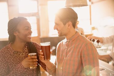 Lächelndes Paar trinkt Bier in einer Bar - HOXF01499