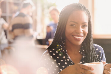 Portrait smiling African woman drinking cappuccino in cafe - HOXF01502