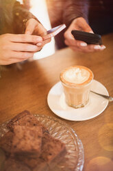 Frauen mit Fotohandys fotografieren Cappuccino-Design am Kaffeetisch - HOXF01519