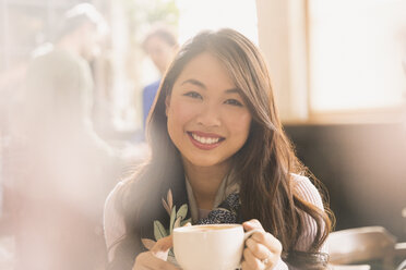 Porträt lächelnde chinesische Frau trinkt Cappuccino im Café - HOXF01524
