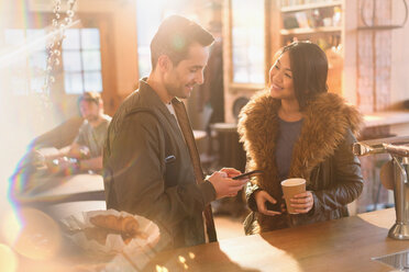 Paar mit Handy und Kaffee am Tresen eines Cafés - HOXF01534