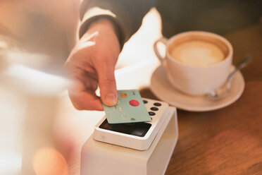 Close up man paying for cappuccino with credit card contactless payment in cafe - HOXF01535