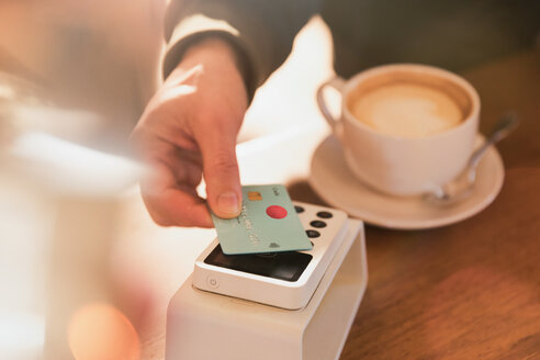 Close up Mann zahlt für Cappuccino mit Kreditkarte kontaktlose Zahlung in Café - HOXF01535