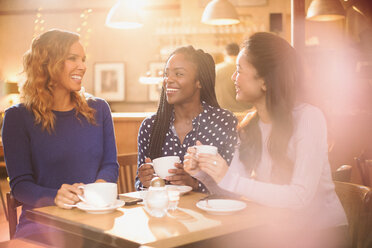 Women friends drinking coffee and talking at cafe table - HOXF01537