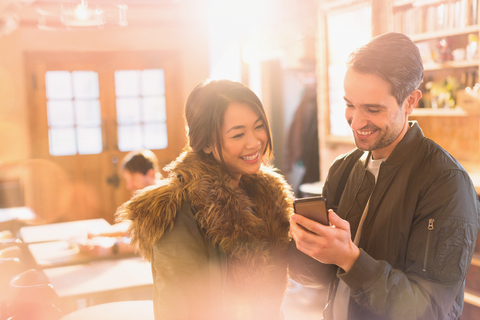 Paar benutzt Mobiltelefon in einem Café, lizenzfreies Stockfoto