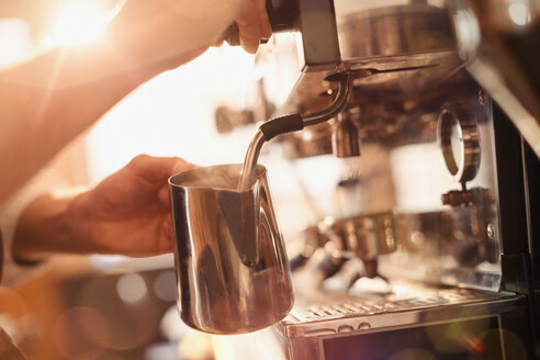 Nahaufnahme eines Barista bei der Verwendung des Milchaufschäumers einer Espressomaschine - HOXF01539