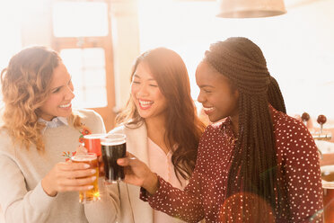 Freundinnen stoßen mit Biergläsern in einer Bar an - HOXF01551