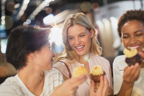 Young women eating cupcakes - HOXF01569