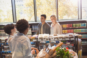 Young friends talking in grocery store market - HOXF01596