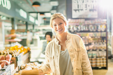 Portrait lächelnde junge Frau beim Einkaufen auf dem Markt - HOXF01600