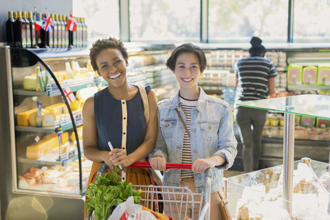 Portrait lächelndes junges lesbisches Paar, Lebensmitteleinkauf auf dem Markt, lizenzfreies Stockfoto