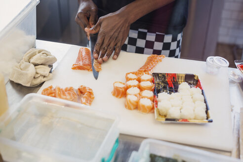 Young female chef slicing salmon, making sushi in restaurant - HOXF01606