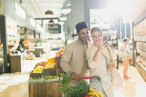 Lächelndes junges Paar macht ein Selfie im Lebensmittelgeschäft, lizenzfreies Stockfoto