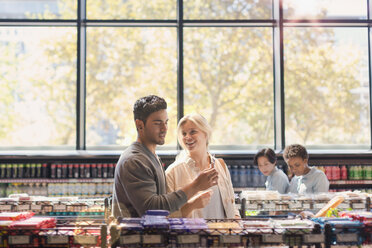 Young couple using cell phone in grocery store market - HOXF01611