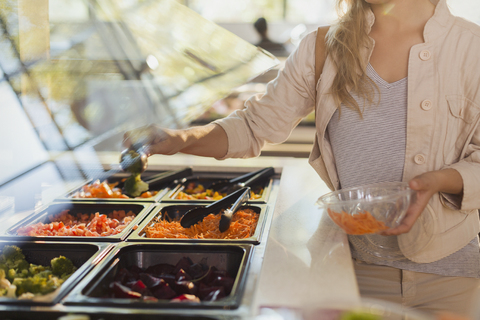 Junge Frau an der Salatbar im Lebensmittelmarkt, lizenzfreies Stockfoto