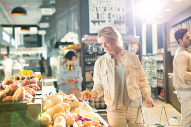 Junge Frau beim Lebensmitteleinkauf, die auf dem Markt nach Produkten sucht - HOXF01633