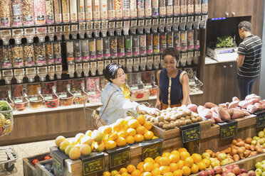 Junge Frauen beim Lebensmitteleinkauf und beim Durchstöbern von Produkten auf dem Markt - HOXF01635