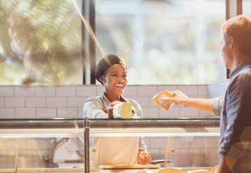 Smiling female worker serving customer at cheese counter in grocery store market - HOXF01657