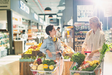 Junge befreundete Frauen mit Einkaufswagen im Gespräch im Lebensmittelmarkt - HOXF01660