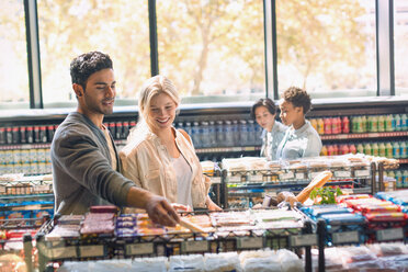 Smiling young couple grocery shopping in market - HOXF01662