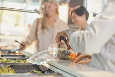 Young woman serving salad at salad bar in grocery store market - HOXF01679