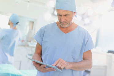 Männlicher Chirurg verwendet digitales Tablet im Operationssaal - HOXF01689