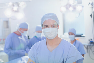 Portrait confident young male surgeon wearing surgical mask in operating room - HOXF01693