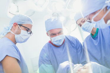 Focused surgeons and anesthesiologist preparing patient for surgery in operating room - HOXF01703