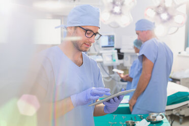 Männlicher Chirurg verwendet digitales Tablet im Operationssaal - HOXF01710