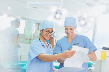 Weibliche Chirurgen bei der Durchsicht von Papierkram im Operationssaal - HOXF01719