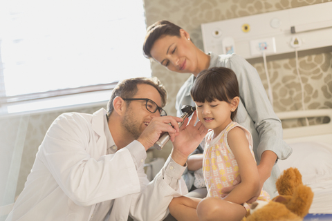 Männlicher Arzt benutzt Otoskop im Ohr einer Patientin im Krankenhaus, lizenzfreies Stockfoto