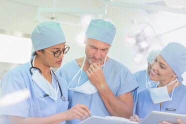 Chirurgen bei der Durchsicht von Papierkram im Operationssaal - HOXF01724