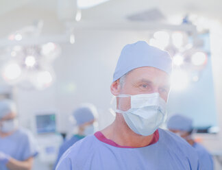 Älterer männlicher Chirurg mit chirurgischer Maske im Operationssaal - HOXF01738