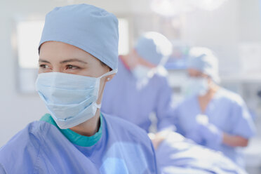 Smiling female surgeon wearing surgical mask in operating room - HOXF01740